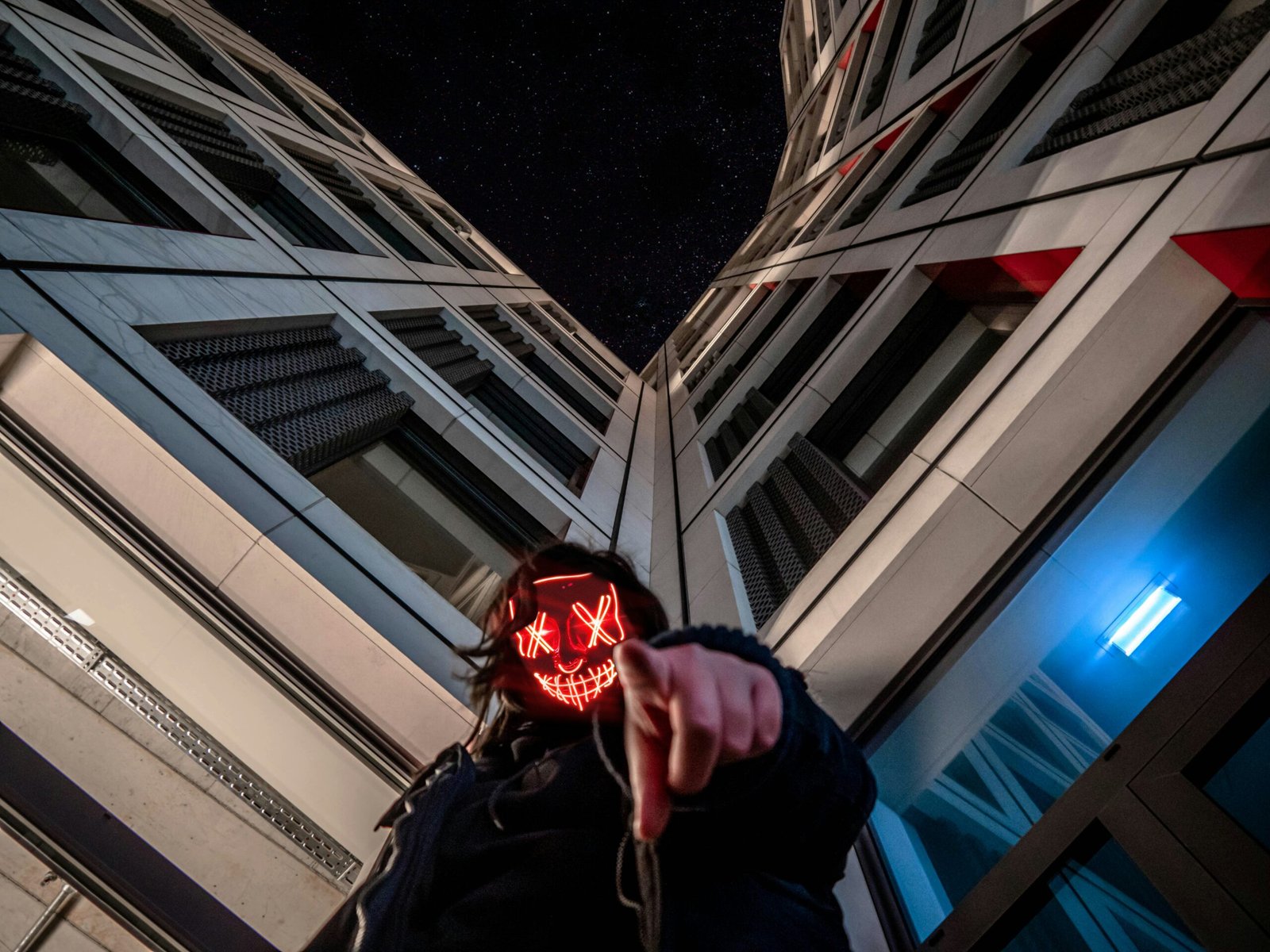 person wearing black jacket standing while pointing finger near high-rise building